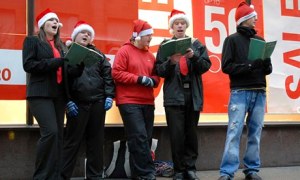 Carol singers wearing Santa hats on a pavement in Glasgow